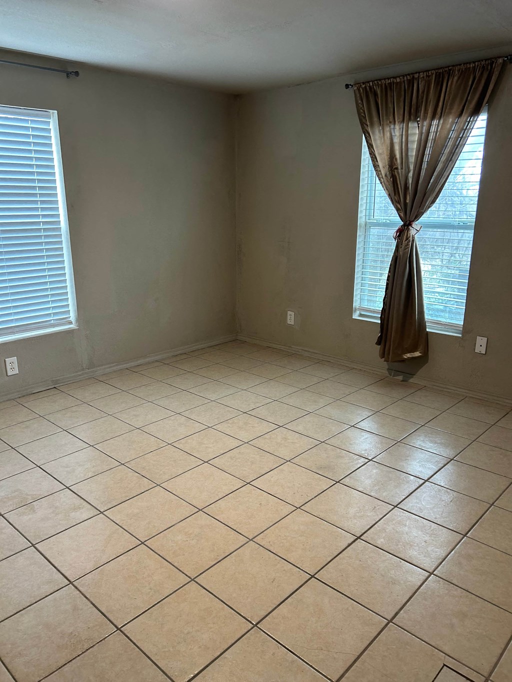 an empty living room with tiled floors and a window