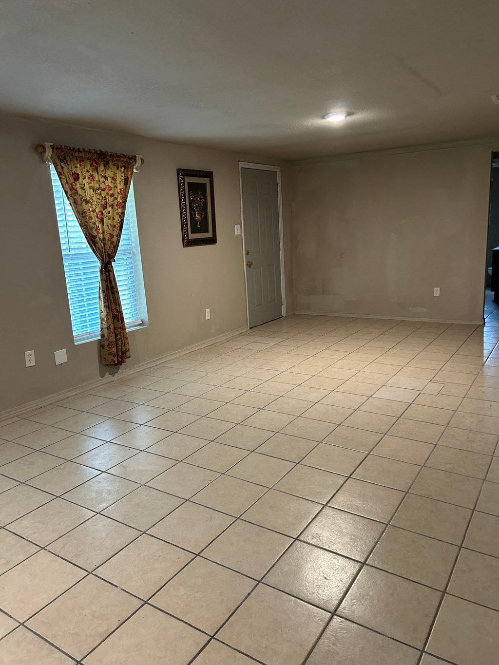 an empty living room with a tiled floor and a door