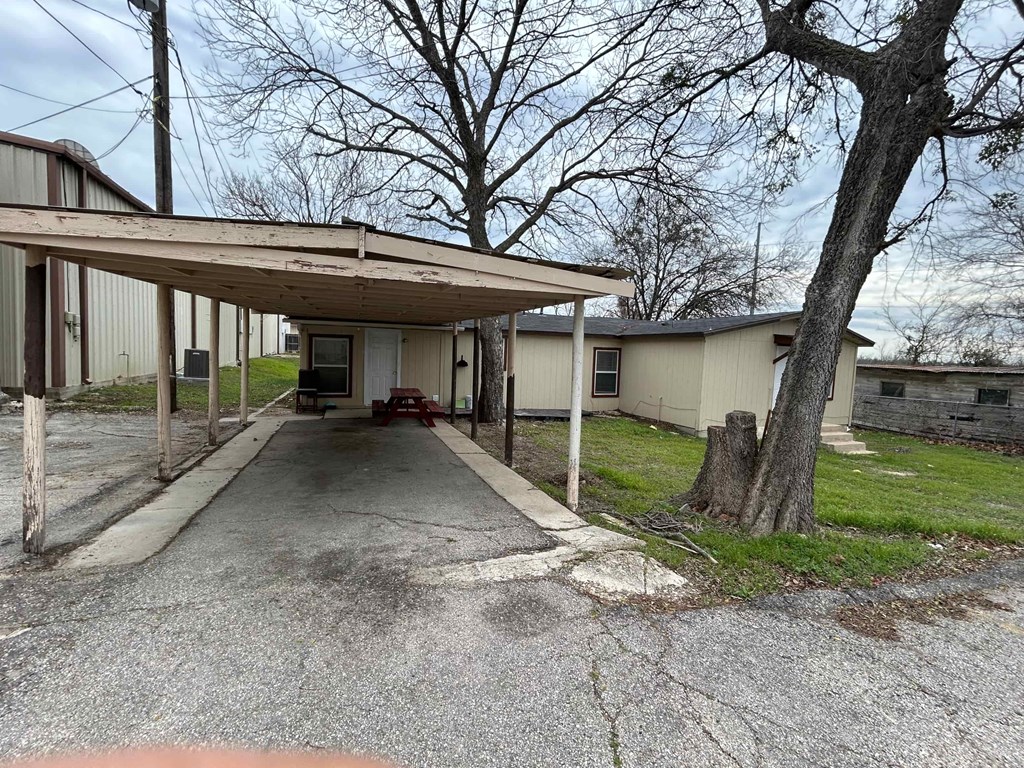 a covered parking lot in front of a white house