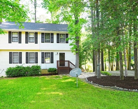 A white house with a green lawn and trees in the background.