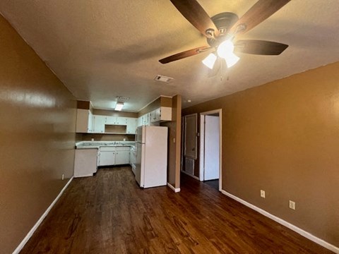 an empty living room and kitchen with a ceiling fan