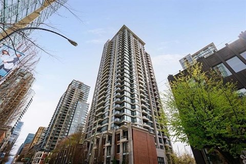 A tall residential building stands in the middle of a city street.