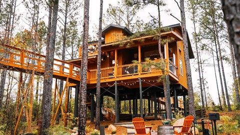 A wooden house with a balcony surrounded by trees.