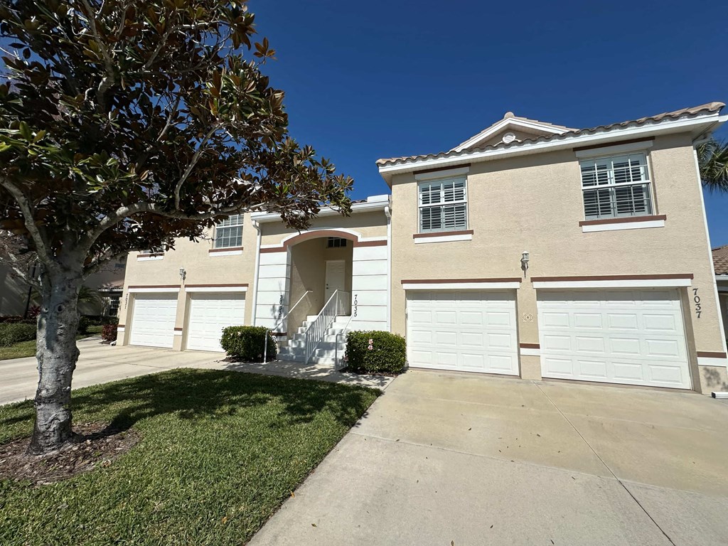 a house with a garage and a tree in front of it