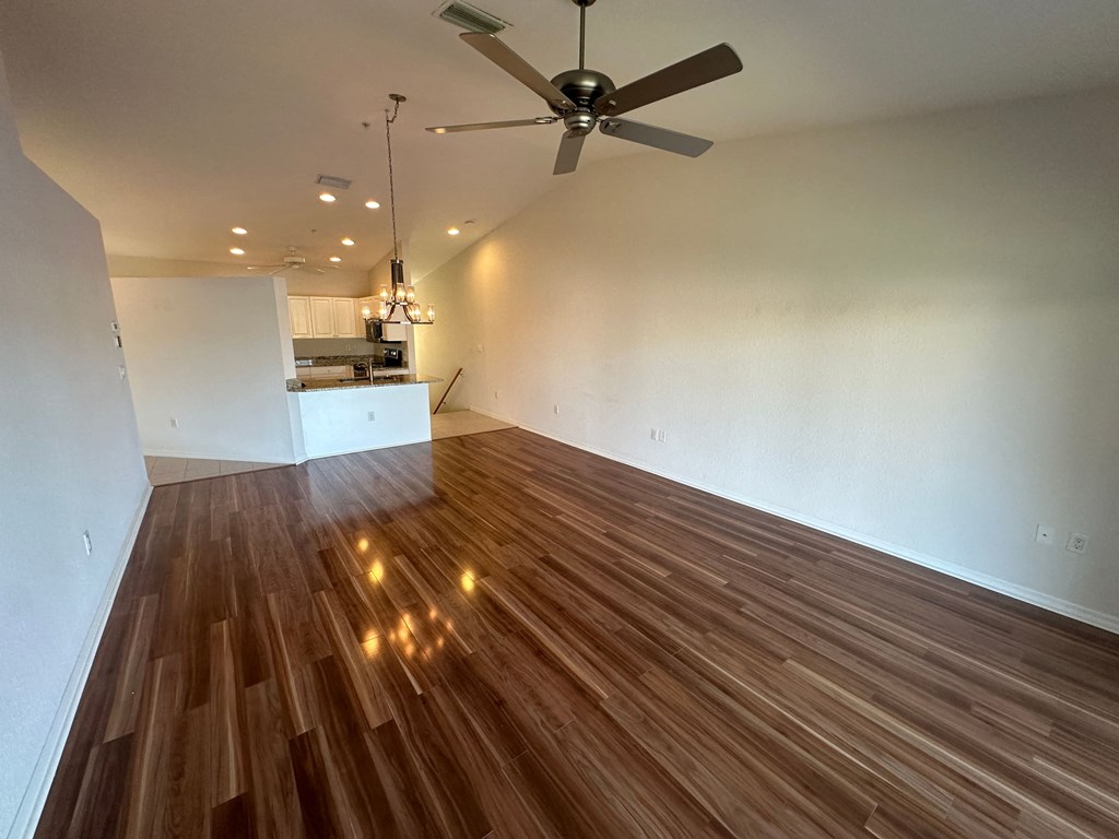 an empty living room with wood flooring and a ceiling fan