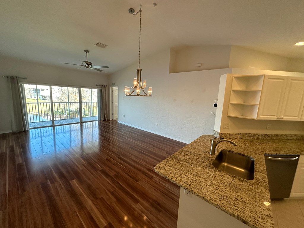 an empty living room and kitchen with hard wood flooring