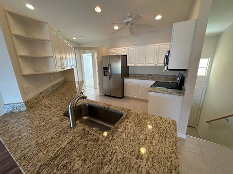a kitchen with granite counter tops and a stainless steel refrigerator