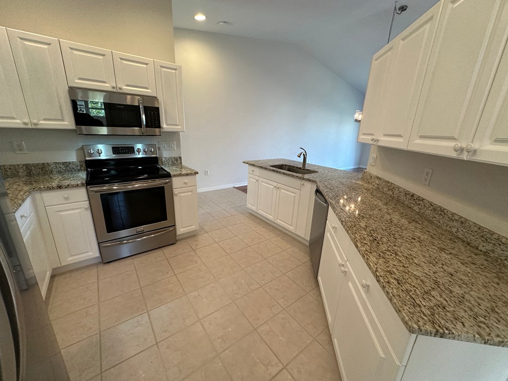 a kitchen with white cabinets and granite counter tops