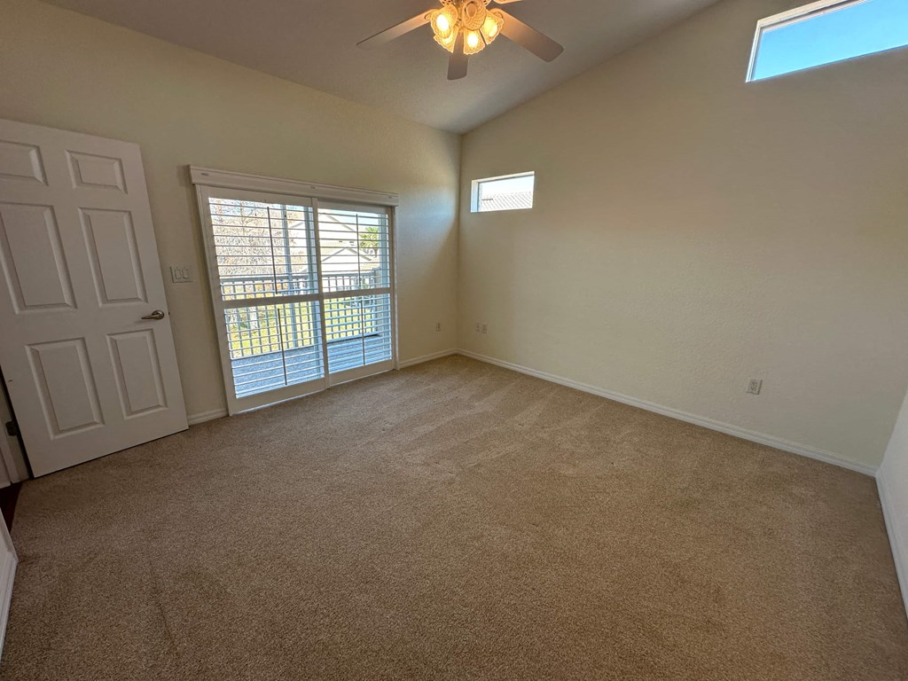 an empty living room with a window and a ceiling fan