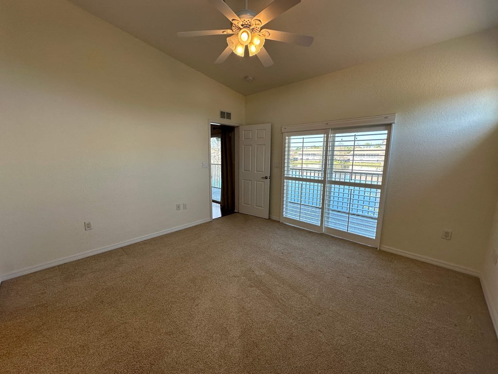 a living room with a ceiling fan and a door to a balcony