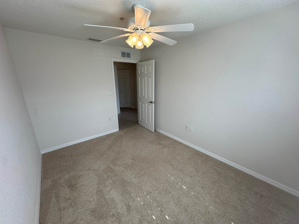 a bedroom with a ceiling fan and carpet