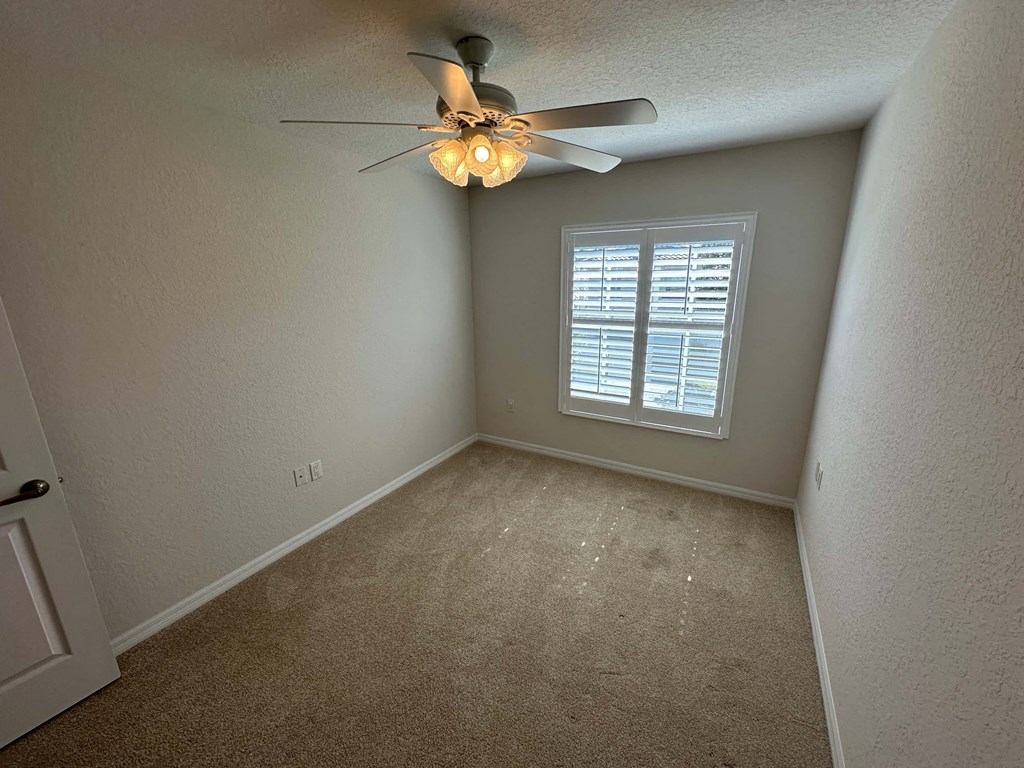 a bedroom with a ceiling fan and a window