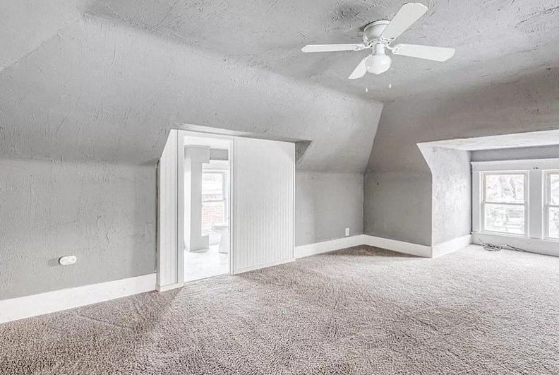 an empty living room with a ceiling fan