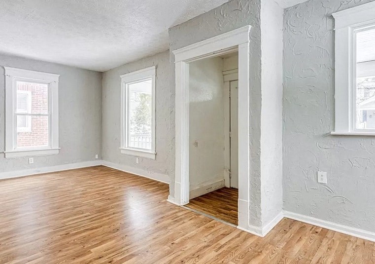an empty living room with wood floors and a doorway
