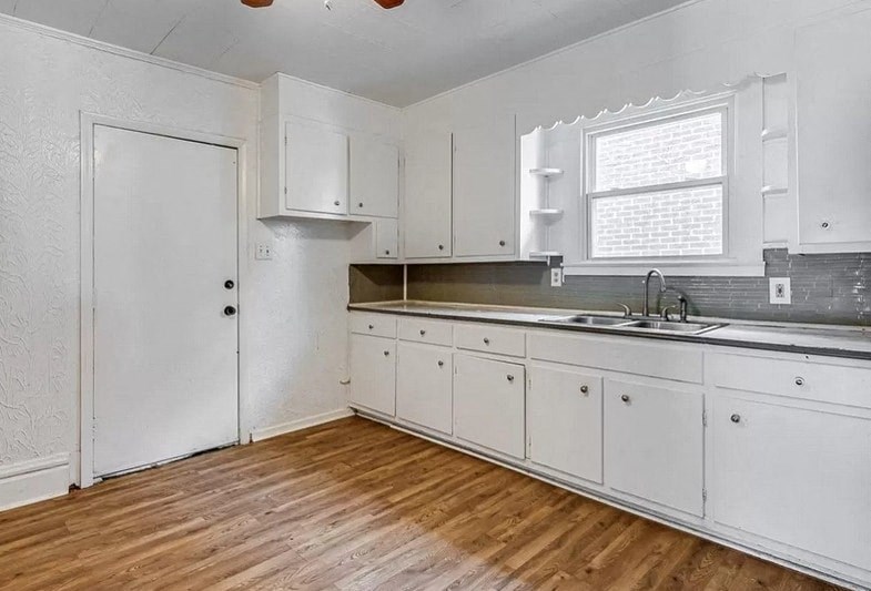 an empty kitchen with white cabinets and a sink