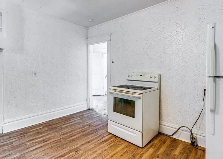 an empty room with a stove and refrigerator in it