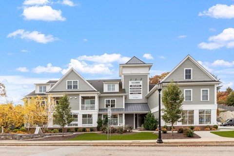 a large gray house with a street in front of it