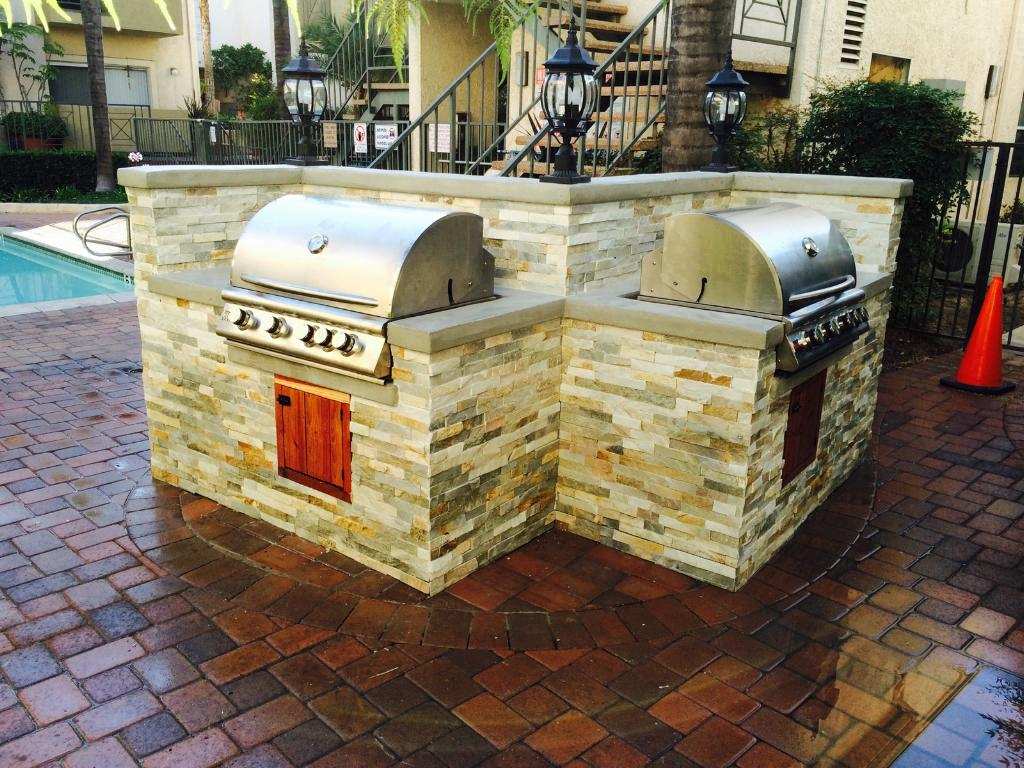 a barbecue grill on a brick patio next to a pool
