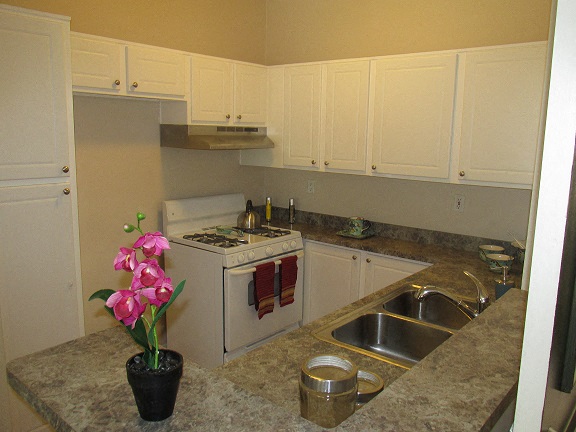 a kitchen with white appliances and a vase with pink flowers