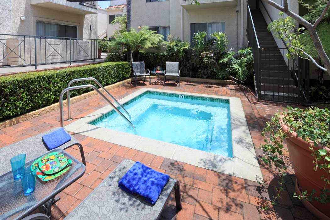 a small pool in a backyard with a table and chairs