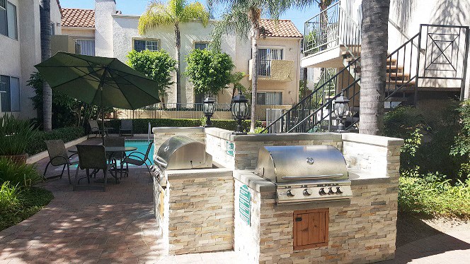a barbecue grill in a backyard with an umbrella