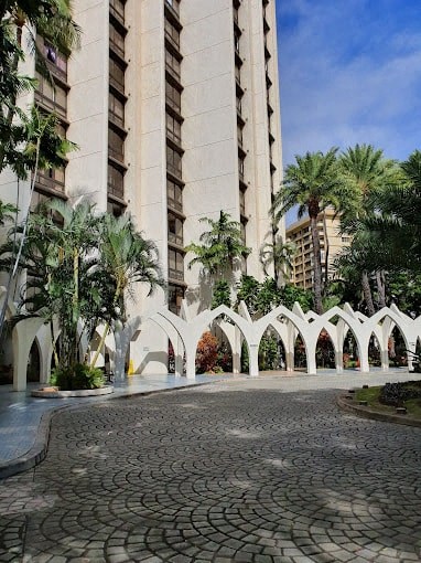 a courtyard with palm trees in front of a tall building