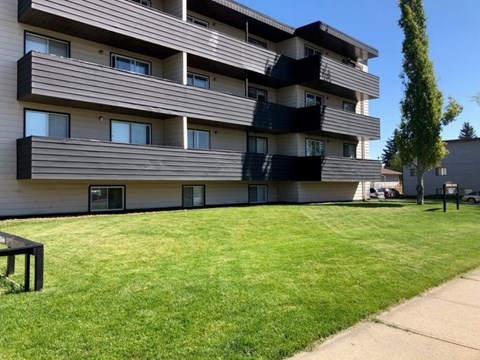 A modern apartment building with a green lawn in front.