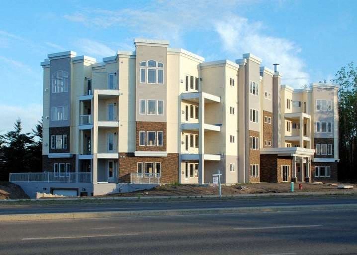 A large, modern apartment building with multiple balconies and doors.