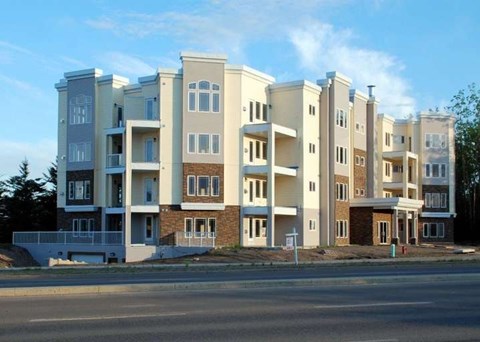A large, modern apartment building with multiple balconies and doors.