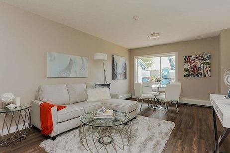 A living room with a white couch, glass coffee table, and a painting on the wall.