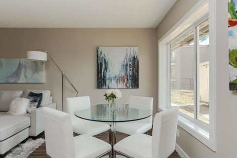 A modern dining room with a glass table and white chairs.