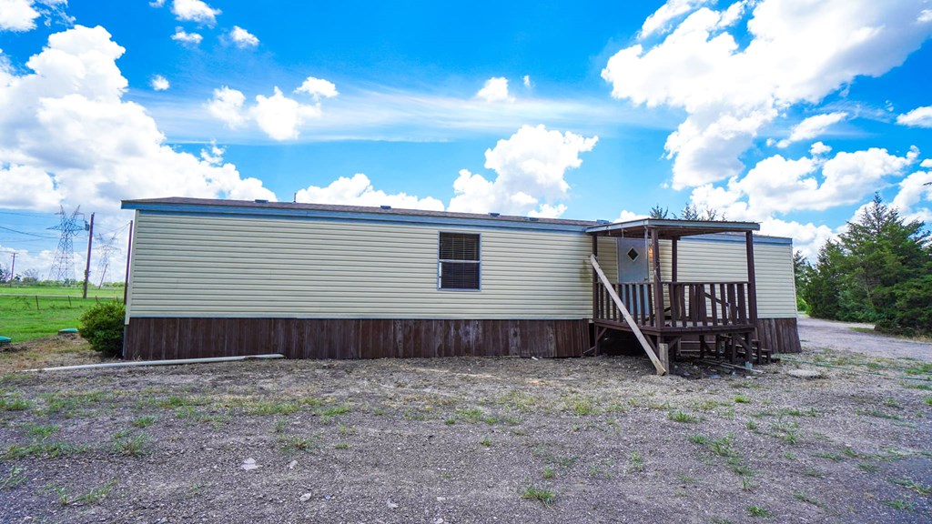 A house with a grey siding and a brown roof with a small deck in front.