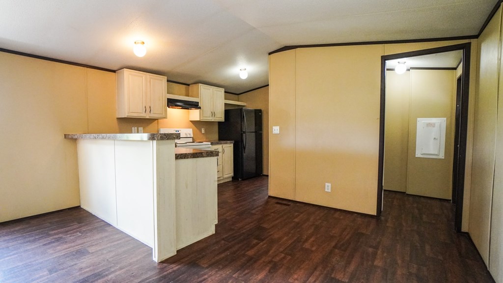 A kitchen with wooden floors and beige walls.