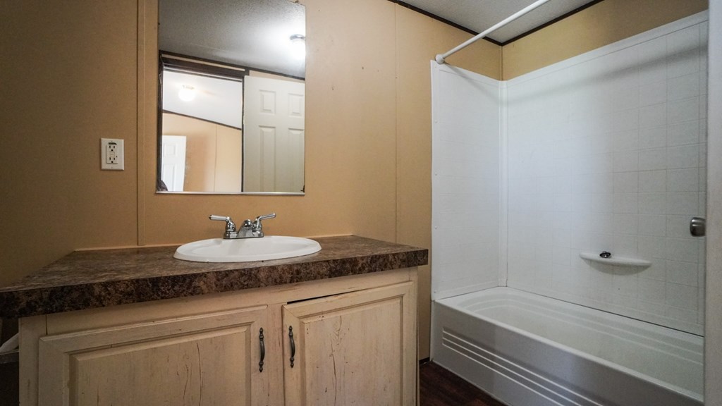 A bathroom with a sink, mirror, and shower.