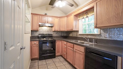 A kitchen with wooden cabinets and black appliances.