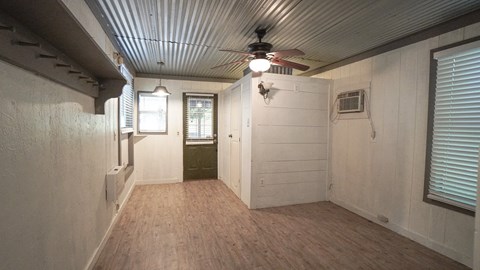 A room with a ceiling fan and a window with blinds.