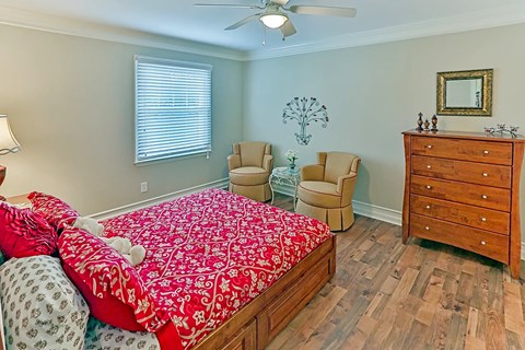 A bedroom with a bed, chair, and dresser.