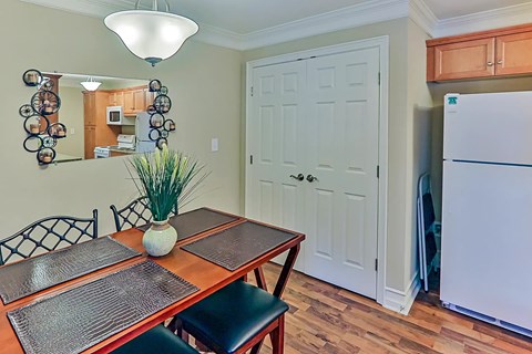 A kitchen with a table and chairs and a fridge.