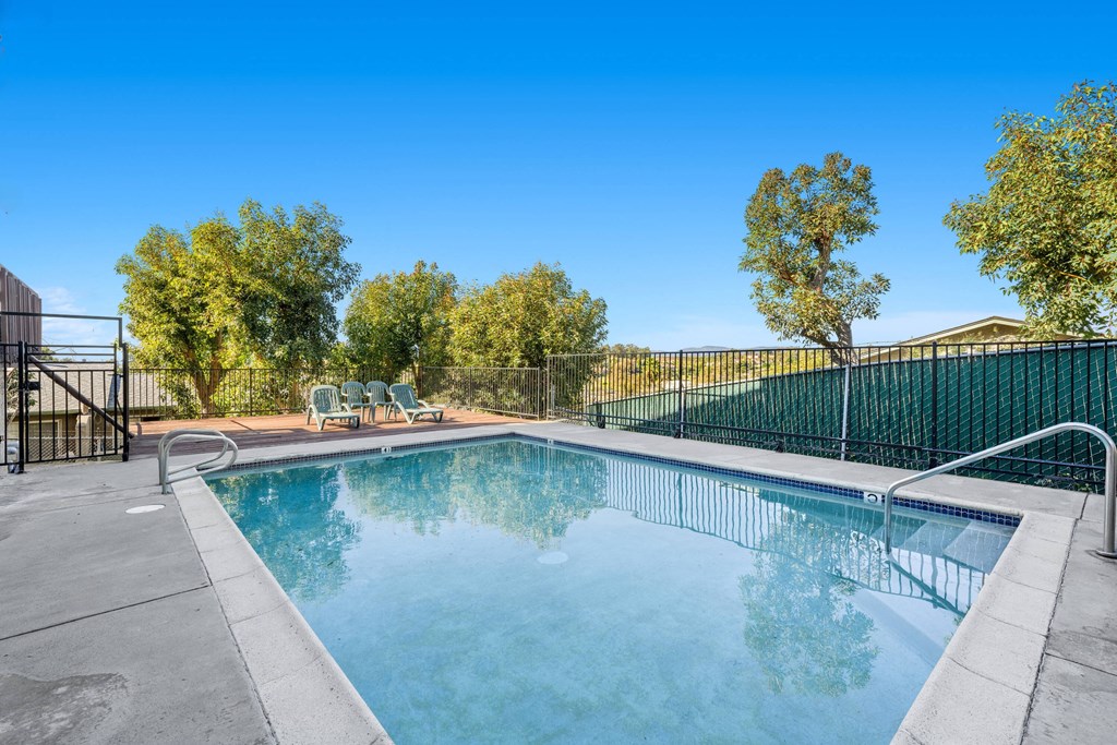 a swimming pool with a fence around it and trees in the background