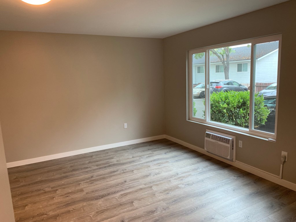 an empty living room with wood floors and a large window