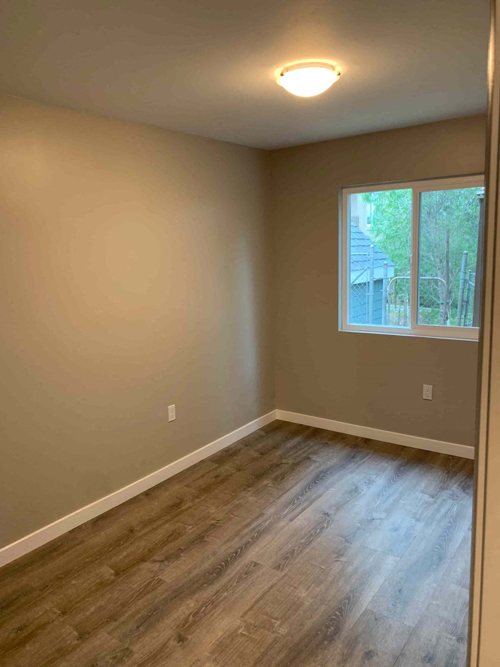 an empty room with wooden floors and a window