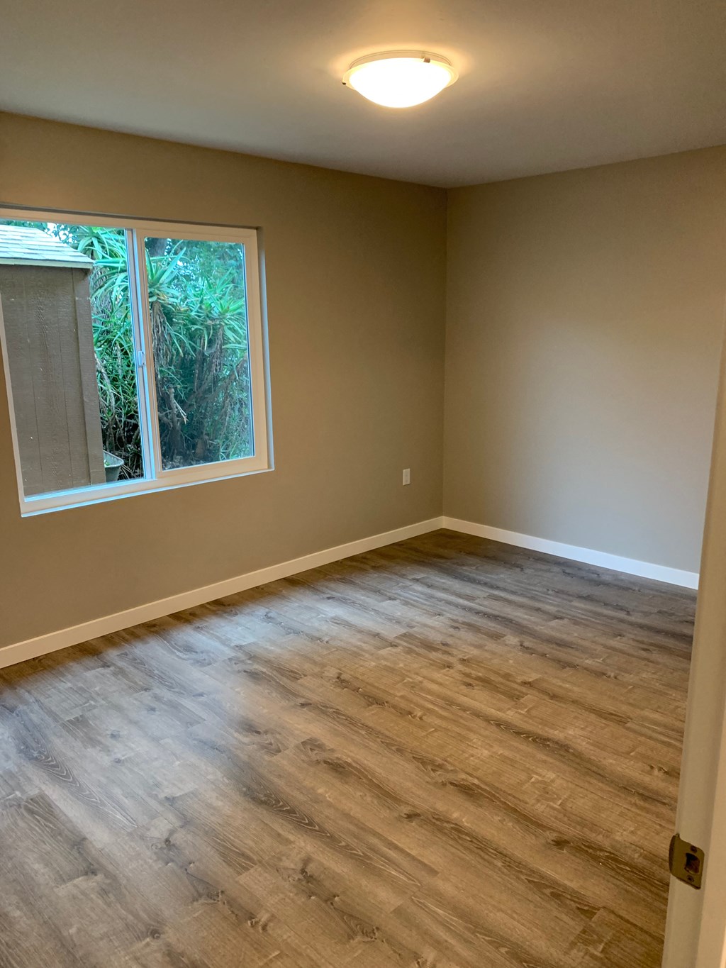 an empty room with a window and wooden floors