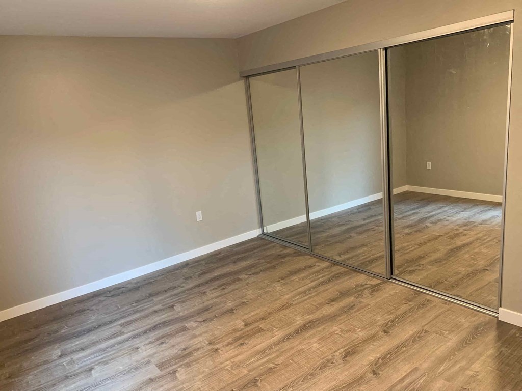a room with wood flooring and mirrored closet doors