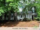 a house surrounded by trees with a dirt driveway