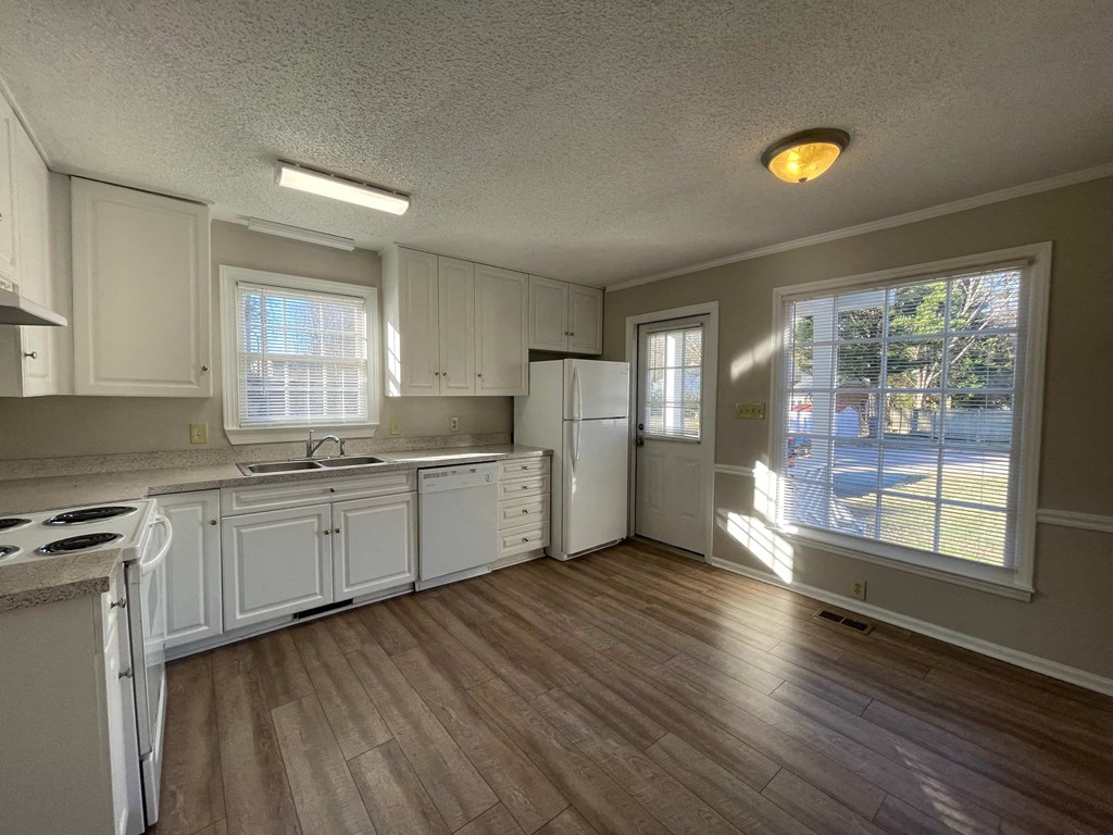 a kitchen with white cabinets and a large window