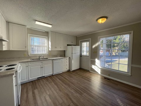 a kitchen with white cabinets and a large window