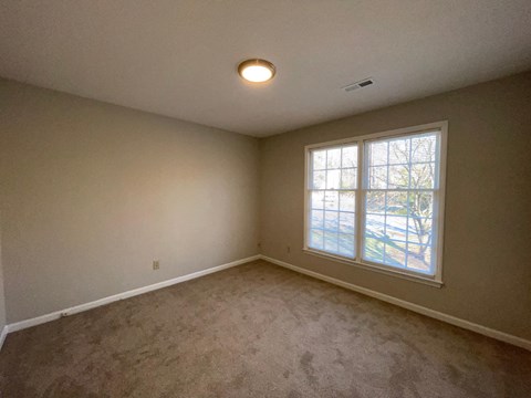an empty living room with a window and carpet