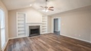 an empty living room with a fireplace and wooden floors