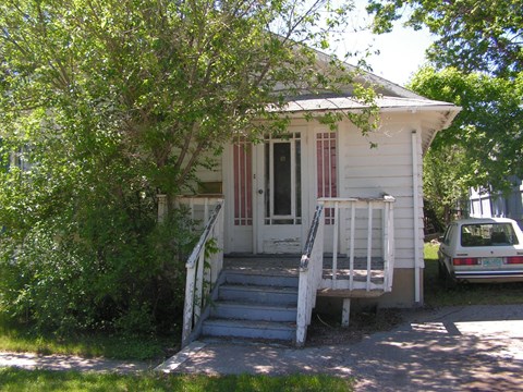 a small white house with a white car parked in front of it