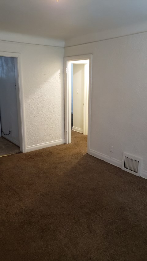 A room with a carpeted floor and a doorway leading to another room.
